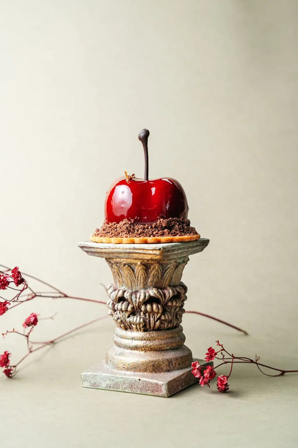 individual dessert with glossy cherry glaze and chocolate base displayed on decorative stand, portioned dessert selection from dessert shop in Wrocław