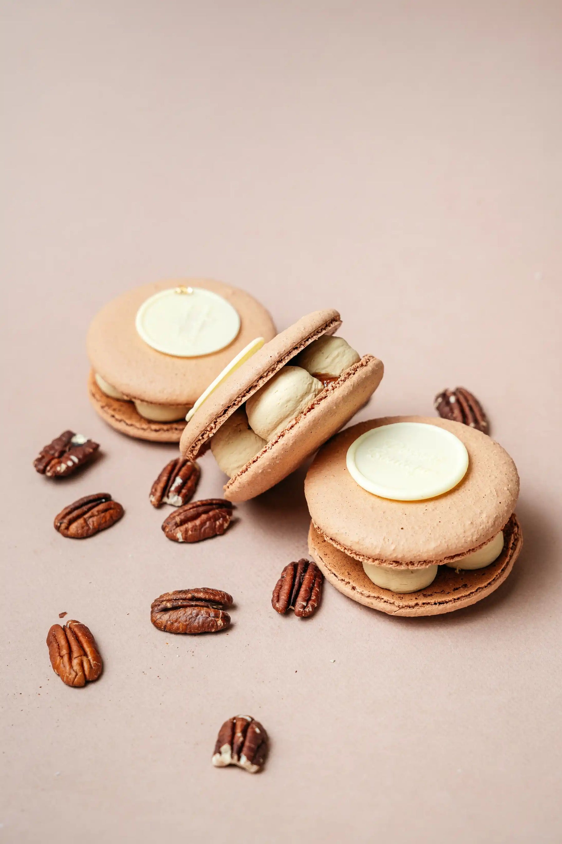 assorted macarons with smooth cream filling and crisp shells arranged with pecans on neutral background, fresh French macarons from bakery in Wrocław