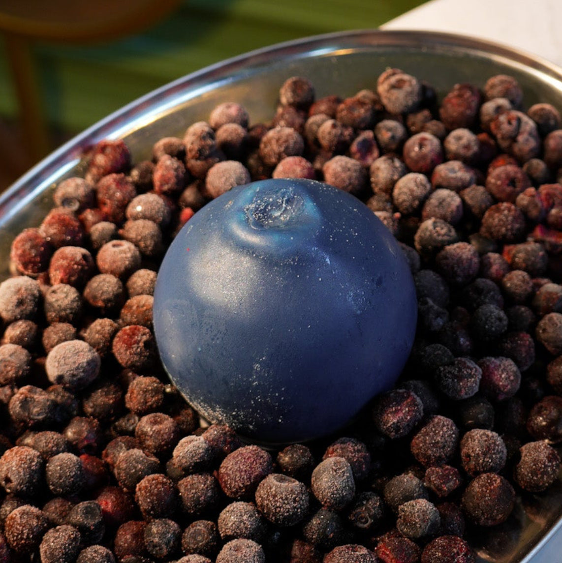Modern 3D mousse dessert sculpted like a large blue berry sitting on a round biscuit base by Dessert Boutique.