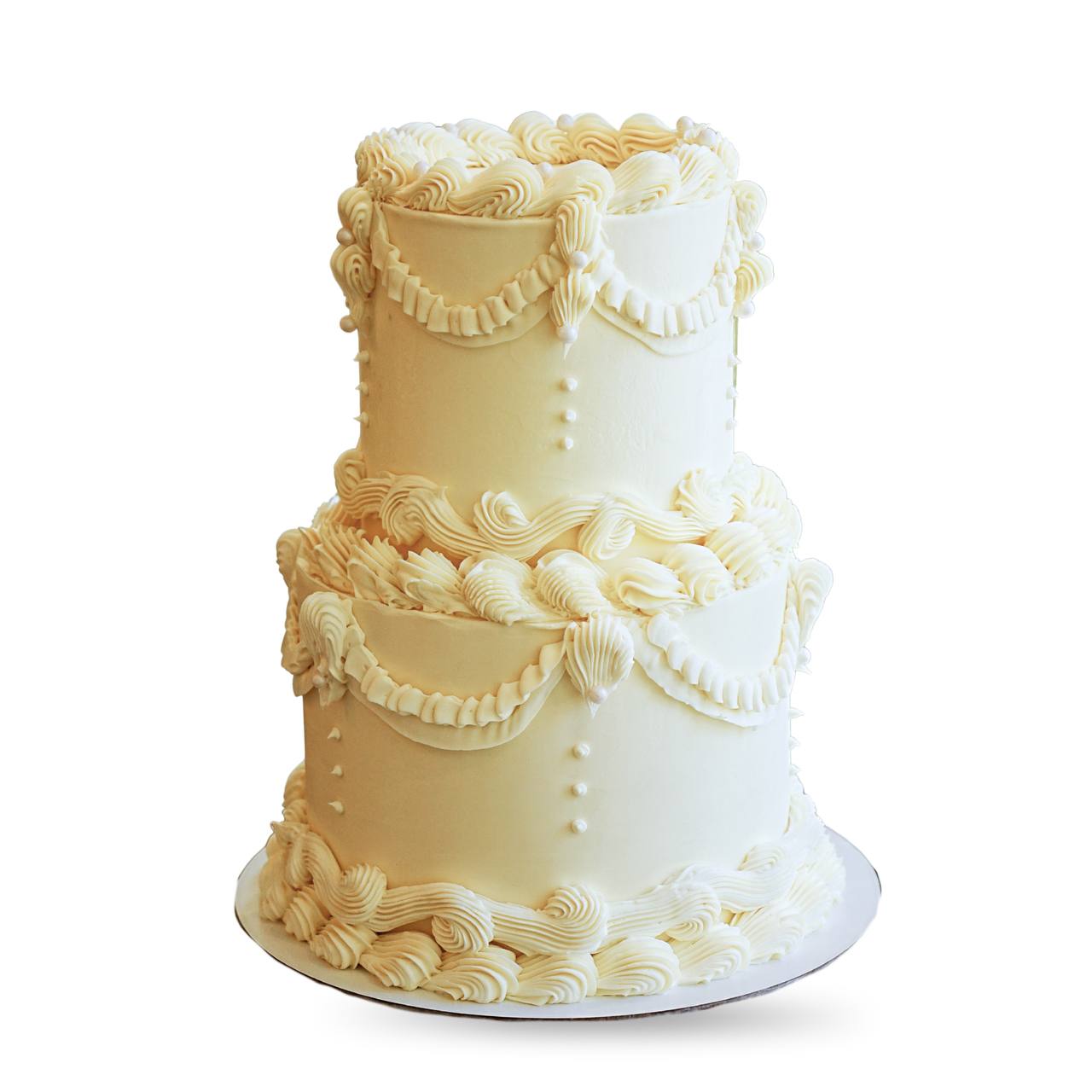 Monochromatic cream colored double tier wedding cake with ornate retro buttercream ruffles and piping by Dessert Boutique.
