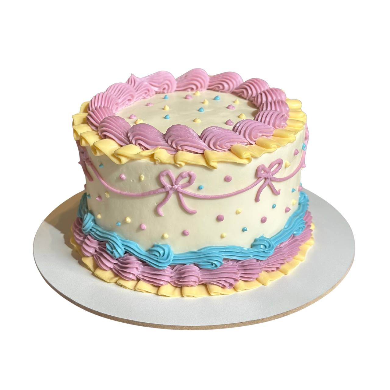 Playful birthday cake decorated with pink buttercream ribbons, yellow ruffles, and blue borders. Available in Wroclaw for sweet birthday parties.