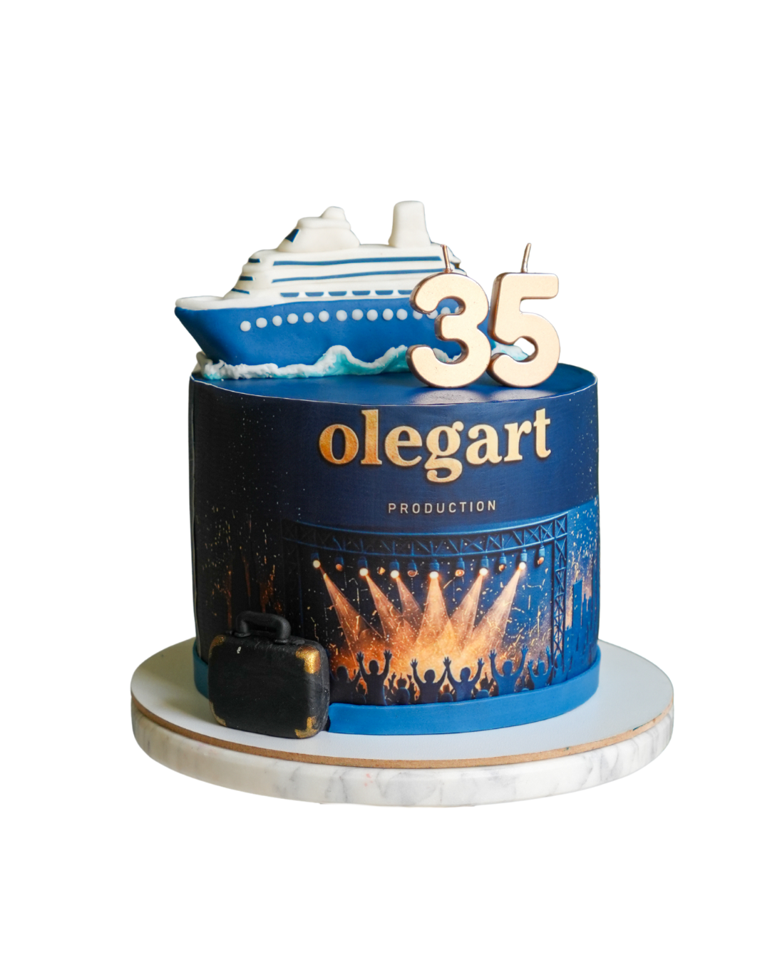 Deep blue anniversary cake showing a large white and blue sugar cruise liner on top and a live concert stage print below by Dessert Boutique.