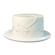 White buttercream cake with a piped pearl cross and gold leaf decorative flakes on the side