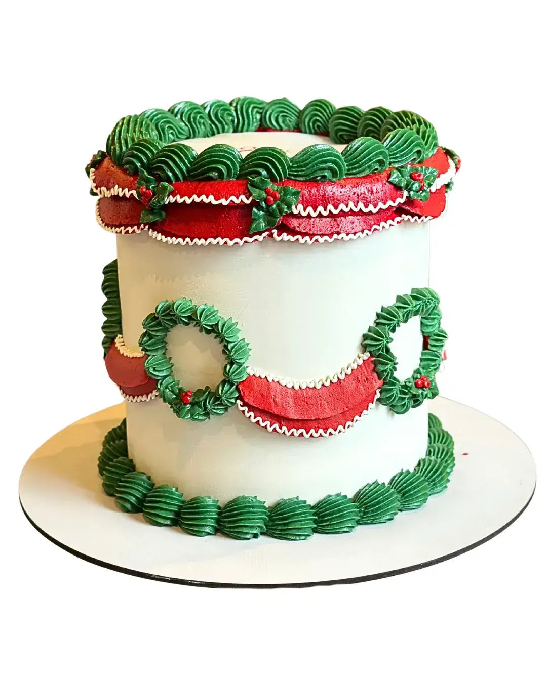 Lambeth-style holiday cake with green piped ruffles, red garlands and wreath decorations on round cake board