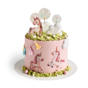 Pink round cake decorated with unicorn cutouts, white clouds, and green moss sponge on top. Dessert Boutique