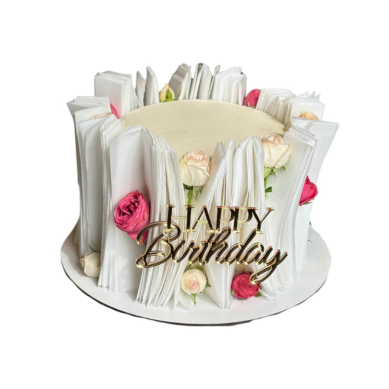White frosted cake wrapped in vertical wafer paper strips, decorated with real pink rosebuds and a golden Happy Birthday topper by Dessert Boutique.