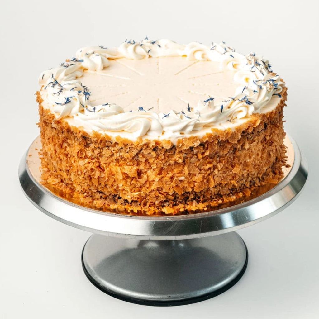 lemon and blackcurrant layer cake with cream cheese frosting, crumb-coated sides and decorative cream border on cake stand