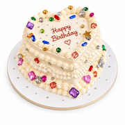 Two tiered heart-shaped cream birthday cake decorated with colorful sugar crystals