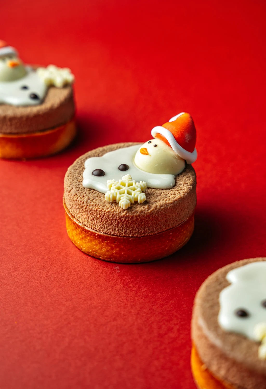 snowman-shaped tart with almond base, coconut dacquoise sponge, vanilla mousse and white chocolate decoration on red background