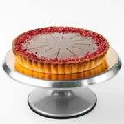 vegan chocolate tart with raspberry topping and glossy cocoa surface on metal cake stand