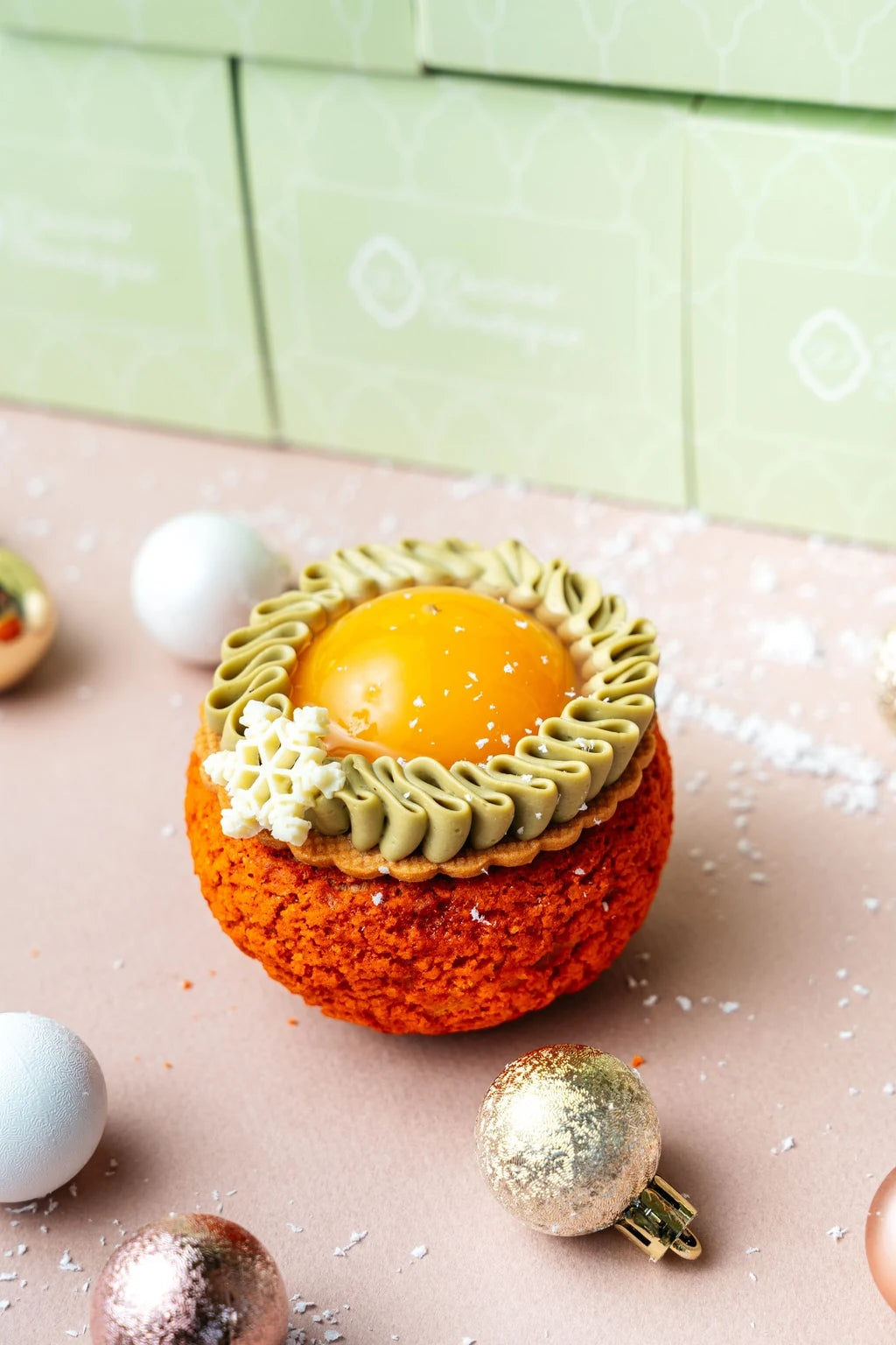 mandarin cream puff with glossy citrus center, pistachio cream piping and textured choux shell on festive surface