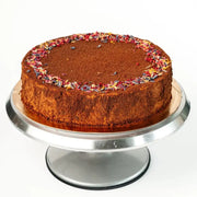 round honey sponge cake with cocoa dusted top and creamy filling on metal cake stand