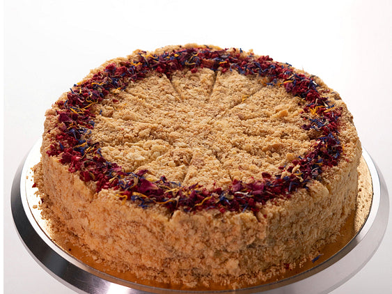 round vanilla Napoleon cake with flaky pastry layers, cream filling and crumb-coated sides on cake stand