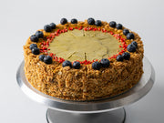 round pistachio Napoleon cake with puff pastry layers, pistachio cream center and nut-coated sides on cake stand