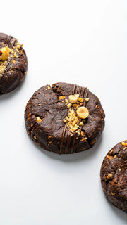 thick chocolate hazelnut cookie with milk chocolate drizzle, roasted nuts and crunchy texture on white background